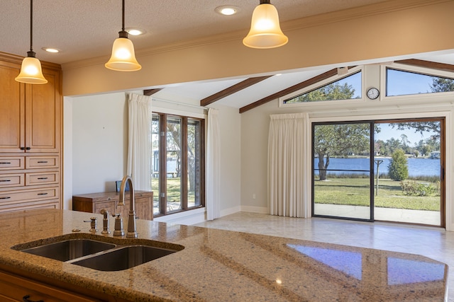 kitchen with a sink, decorative light fixtures, lofted ceiling with beams, a textured ceiling, and light stone countertops