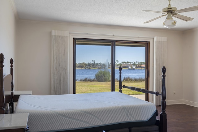 bedroom with a water view, access to outside, a textured ceiling, dark wood finished floors, and baseboards