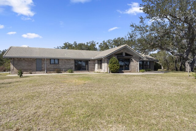 view of front facade with brick siding, a tile roof, and a front yard