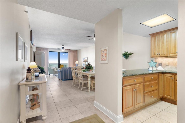 kitchen featuring light tile patterned floors, tasteful backsplash, dark stone countertops, and a textured ceiling