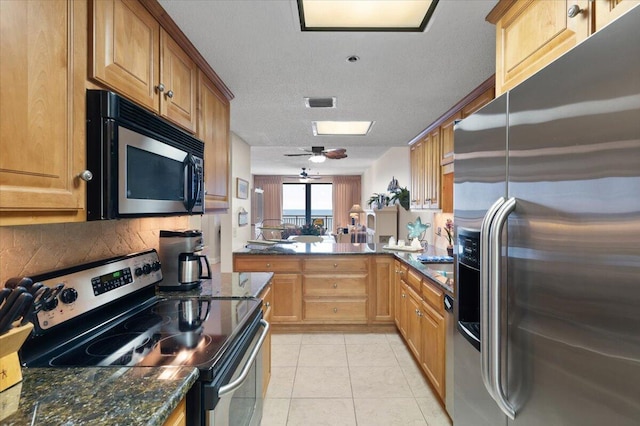 kitchen with light tile patterned floors, ceiling fan, stainless steel appliances, decorative backsplash, and dark stone countertops