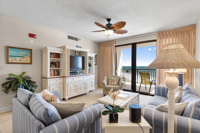 living area with visible vents, light tile patterned flooring, ceiling fan, a textured ceiling, and baseboards