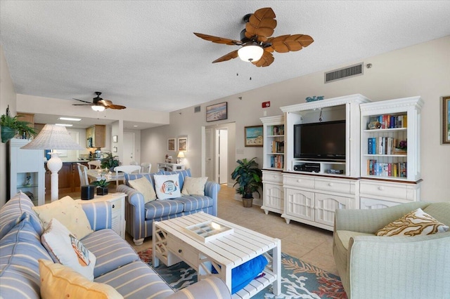 living room featuring light tile patterned floors, a ceiling fan, visible vents, and a textured ceiling