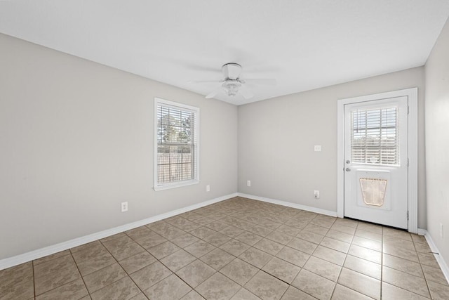 empty room featuring ceiling fan, light tile patterned floors, and baseboards