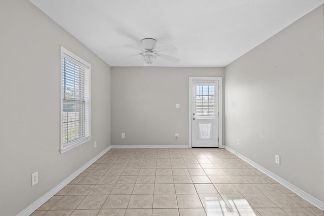 empty room featuring baseboards, a ceiling fan, and light tile patterned flooring