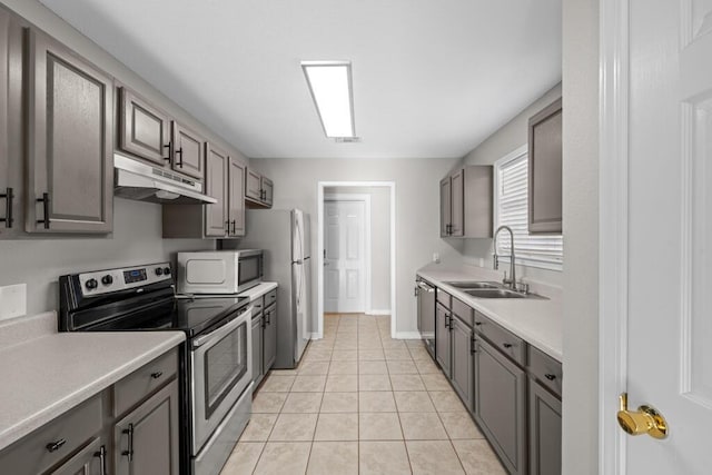 kitchen featuring appliances with stainless steel finishes, a sink, under cabinet range hood, and gray cabinetry