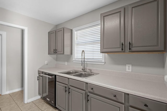 kitchen featuring a sink, stainless steel dishwasher, light tile patterned flooring, and gray cabinets