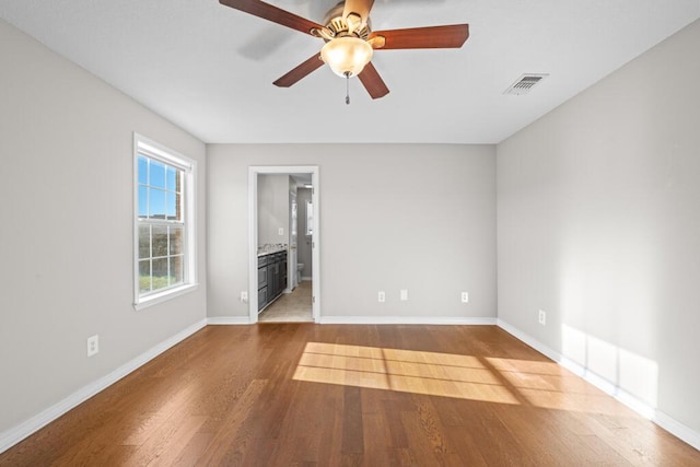 unfurnished room featuring a ceiling fan, wood finished floors, visible vents, and baseboards