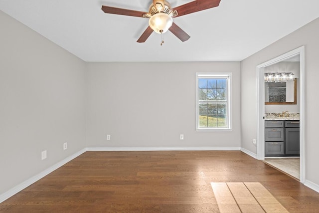 empty room with ceiling fan, dark wood-type flooring, and baseboards