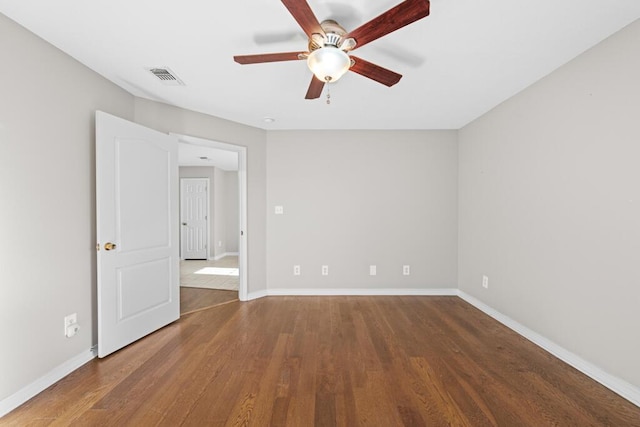 spare room featuring a ceiling fan, wood finished floors, visible vents, and baseboards