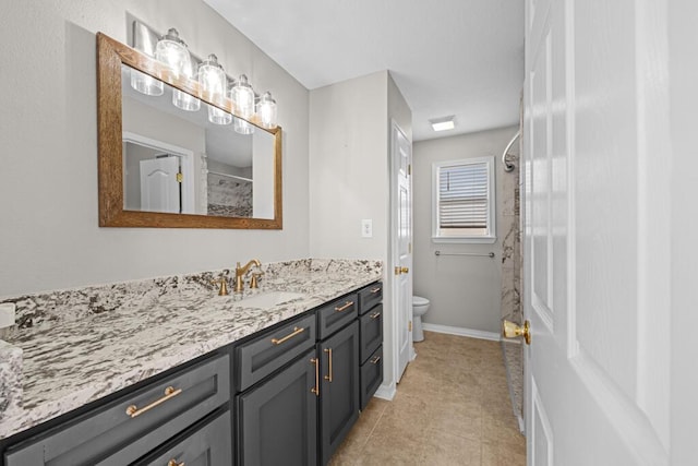 bathroom featuring toilet, vanity, baseboards, tile patterned floors, and walk in shower