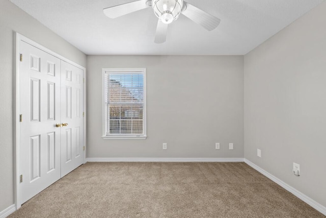 carpeted empty room with ceiling fan and baseboards