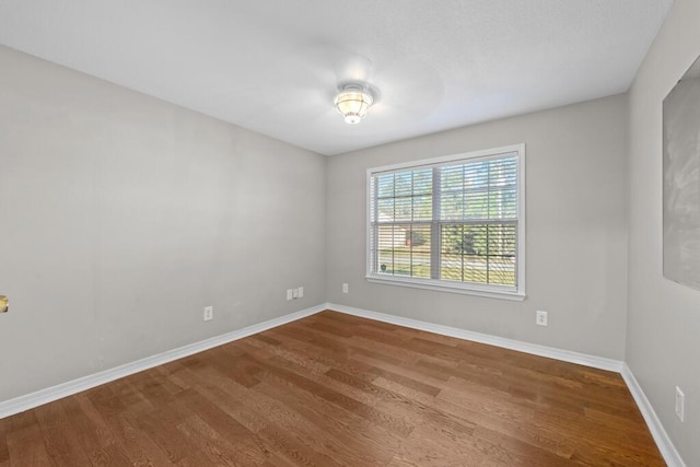 unfurnished room with baseboards and wood finished floors