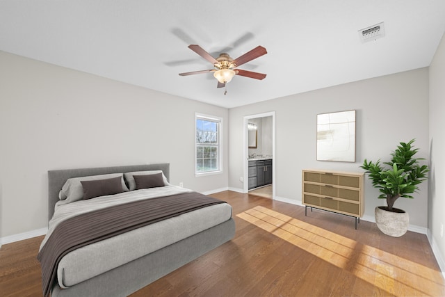 bedroom featuring baseboards, visible vents, wood finished floors, and ensuite bathroom