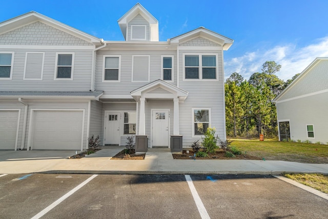 view of property featuring a garage, uncovered parking, and a front yard