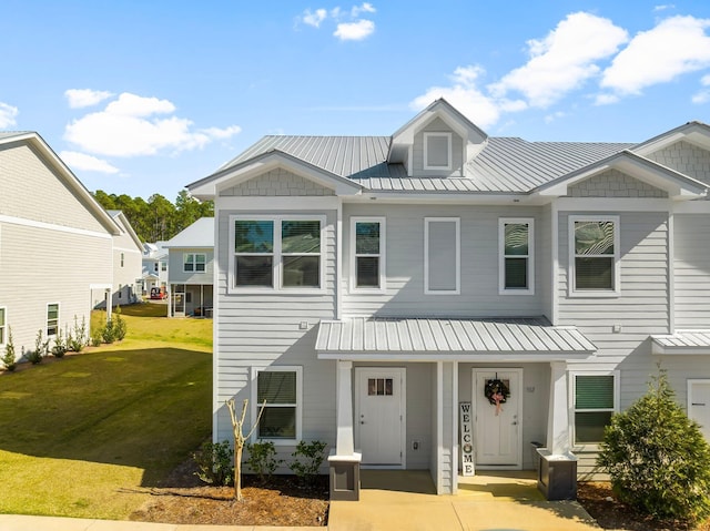 view of front of house featuring a front lawn, covered porch, and metal roof