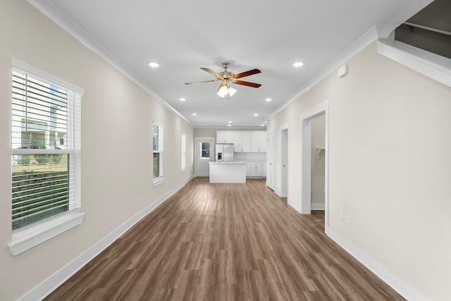 unfurnished living room with recessed lighting, crown molding, baseboards, and wood finished floors