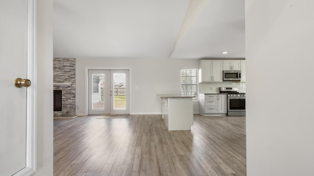 kitchen with french doors, stainless steel appliances, decorative backsplash, light wood-style floors, and open floor plan