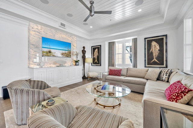 living area with a tray ceiling, ornamental molding, wooden ceiling, and visible vents