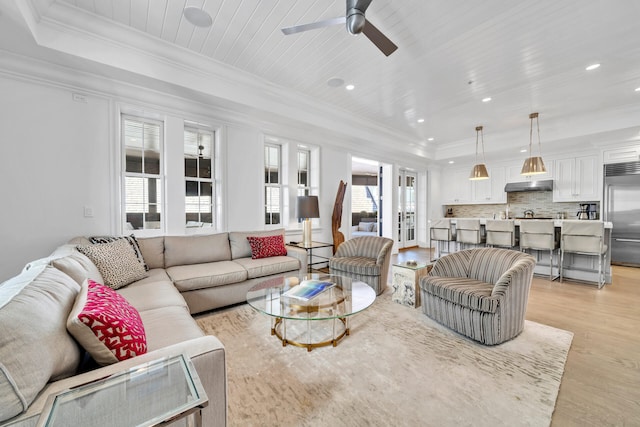 living room featuring a tray ceiling, crown molding, light wood finished floors, recessed lighting, and wood ceiling