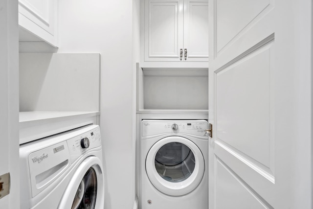 clothes washing area with washer and dryer and cabinet space