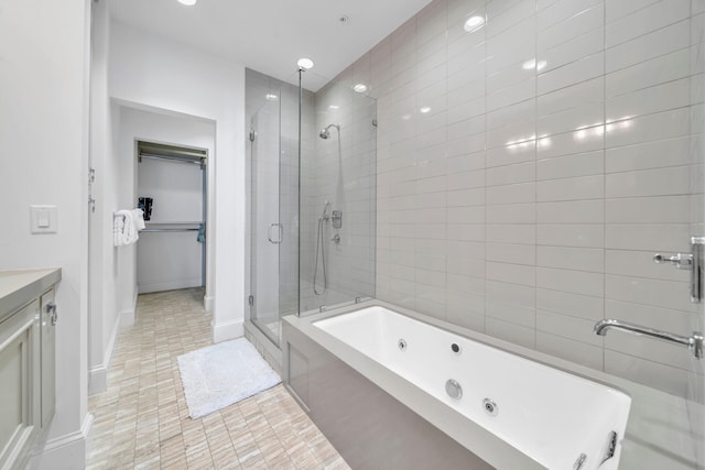 bathroom with a tub with jets, tile patterned floors, a spacious closet, vanity, and a shower stall