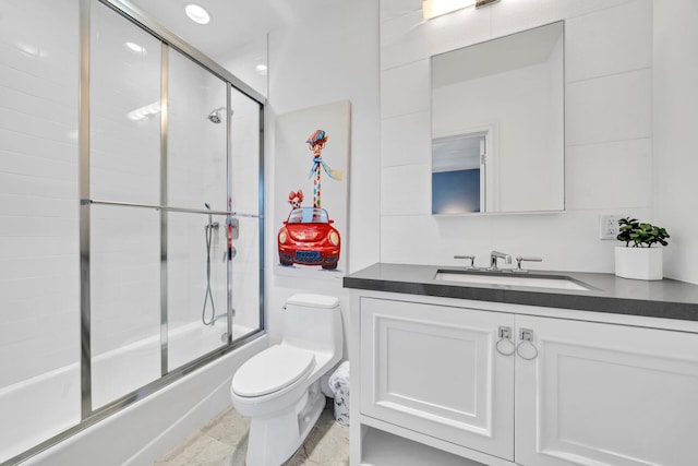 full bathroom featuring toilet, combined bath / shower with glass door, and vanity