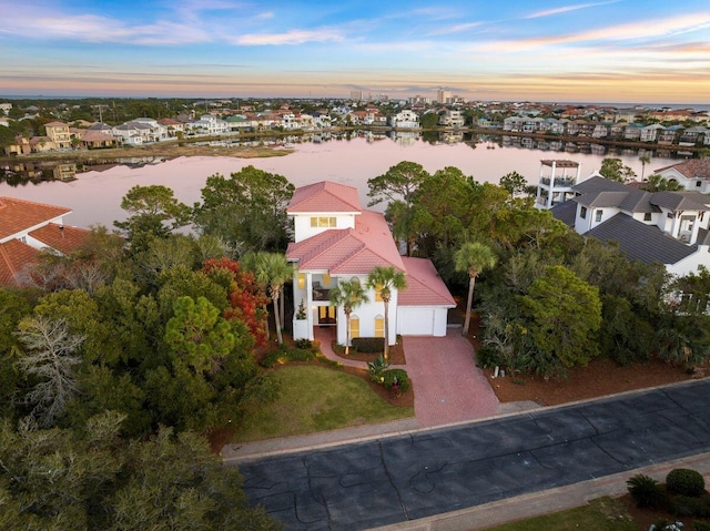 aerial view at dusk featuring a water view and a residential view