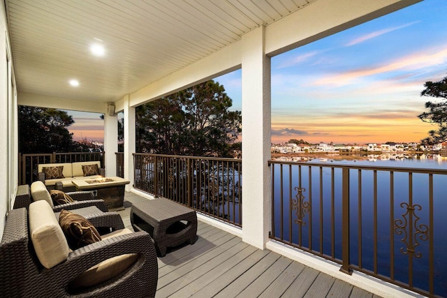 wooden terrace with an outdoor living space with a fire pit and a water view