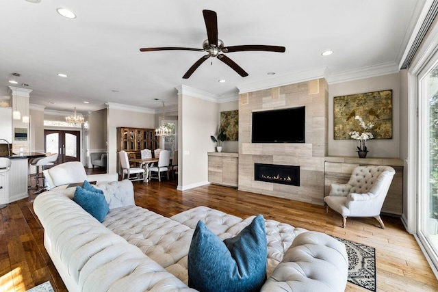 living room with ornamental molding, hardwood / wood-style floors, a fireplace, and recessed lighting