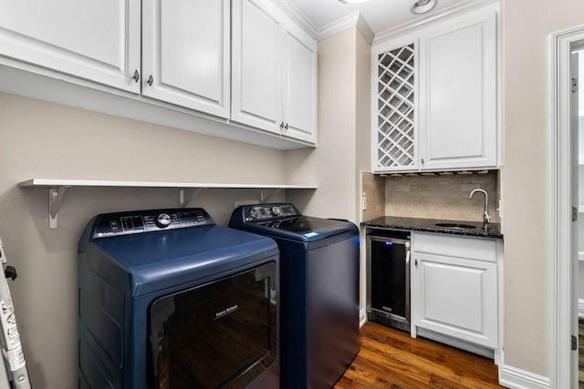 laundry room with dark wood finished floors, a sink, laundry area, washer and dryer, and beverage cooler