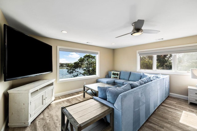 living area with light wood-type flooring, a wealth of natural light, visible vents, and baseboards