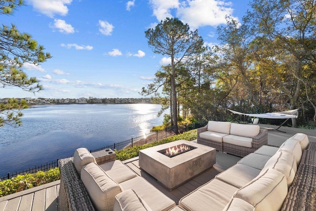 view of patio featuring a water view, an outdoor living space with a fire pit, and fence