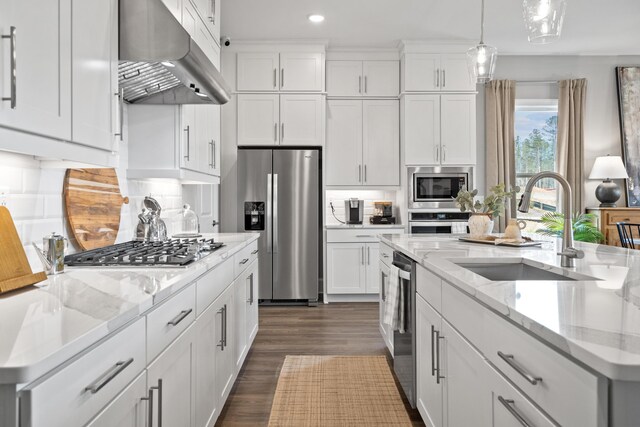 kitchen with under cabinet range hood, appliances with stainless steel finishes, white cabinets, and a sink