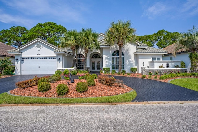 mediterranean / spanish home featuring aphalt driveway, french doors, a tile roof, stucco siding, and a garage