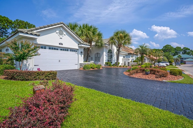 view of front of home featuring a garage, a tiled roof, decorative driveway, and stucco siding