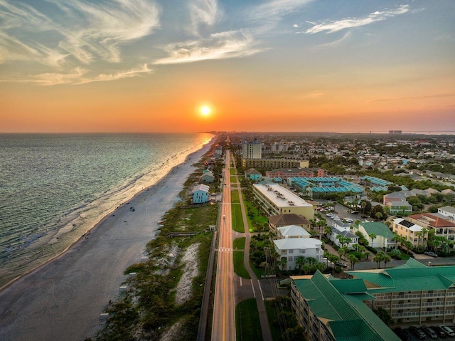 aerial view at dusk featuring a water view and a view of the beach