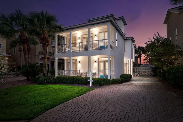 view of front of property featuring a balcony, a front lawn, and stucco siding