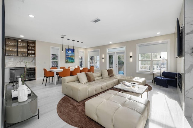 living area featuring visible vents, light wood-style flooring, wine cooler, a bar, and recessed lighting