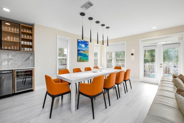 dining room featuring beverage cooler, a dry bar, baseboards, and a healthy amount of sunlight