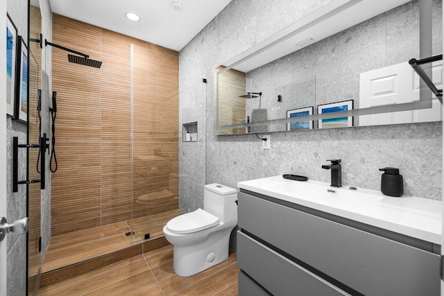 bathroom featuring tiled shower, tile walls, toilet, and vanity