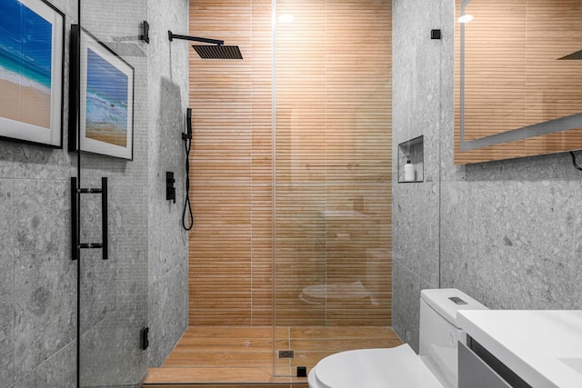 bathroom with tile walls, a shower stall, toilet, and vanity