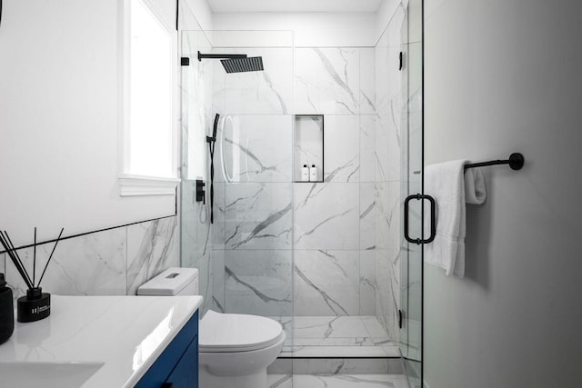 full bath with toilet, marble finish floor, a marble finish shower, and vanity