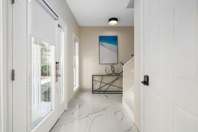 doorway to outside featuring marble finish floor and baseboards