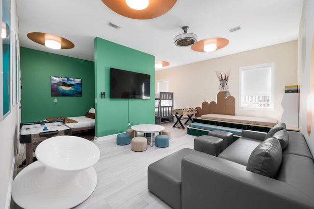 living area featuring baseboards, visible vents, and wood finished floors