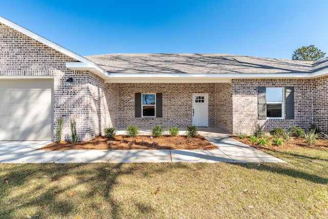 property entrance featuring a yard, brick siding, roof with shingles, and an attached garage