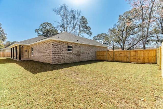 exterior space featuring a fenced backyard, ceiling fan, brick siding, and a lawn