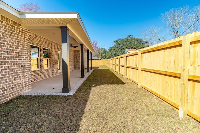 view of yard with a ceiling fan, a fenced backyard, and a patio