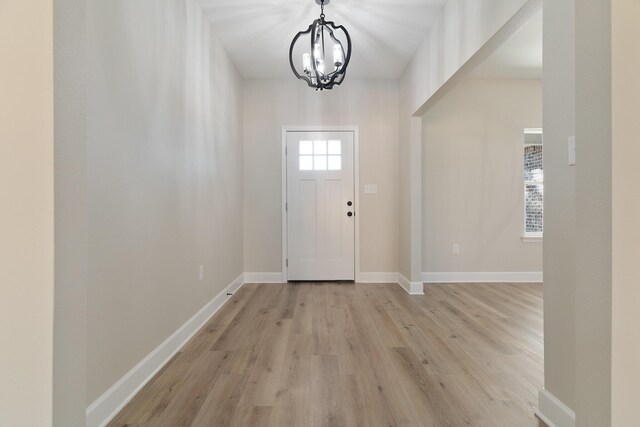 foyer entrance with baseboards, a chandelier, and light wood-style floors