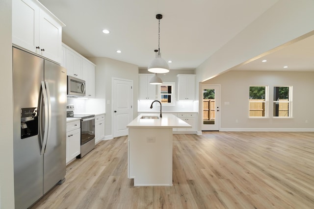 kitchen with light wood-style flooring, appliances with stainless steel finishes, a kitchen island with sink, light countertops, and a sink